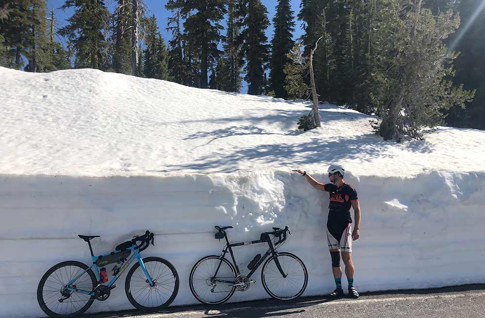 photo of a rider standing next to a snowbank in July on the road to Mount Lassen